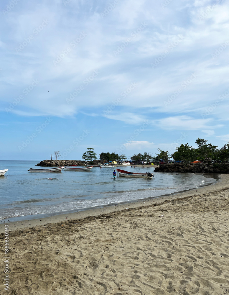 Beautiful beach and tropical sea, dreamy sky under the sunlight, small fishing boat next to rocks and vegetation Beautiful beach and tropical sea, dreamy sky under the sunlight, small fishing boat next to rocks and vegetation