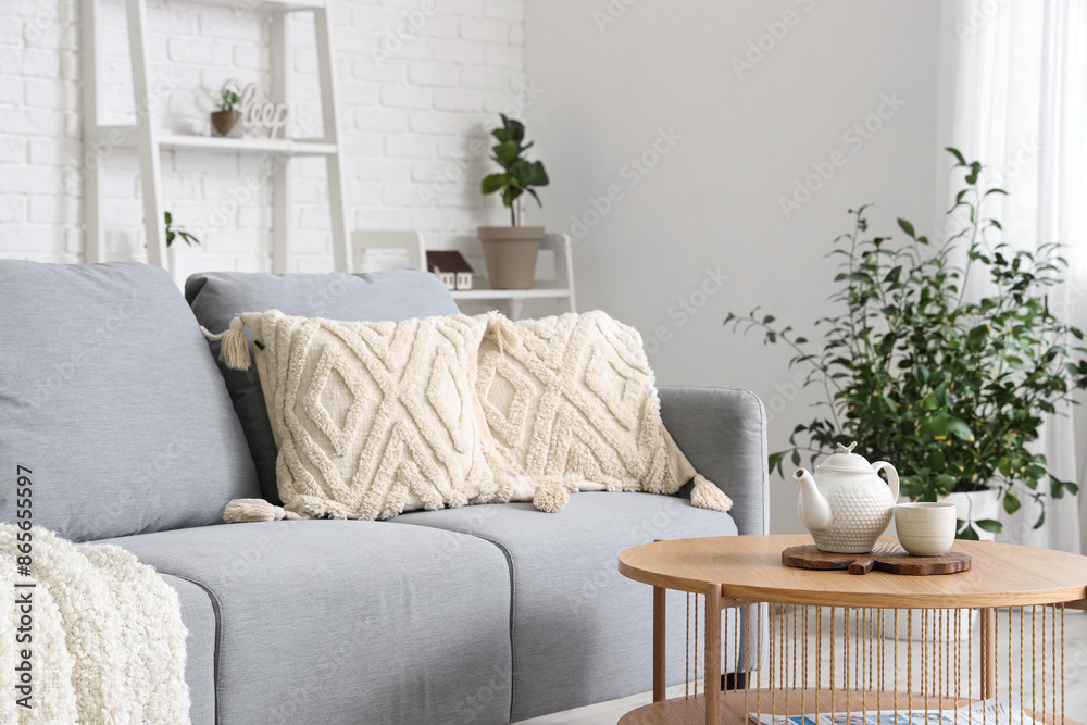 Naklejka premium Stylish interior of living room with cozy sofa, houseplant, cushions and coffee table