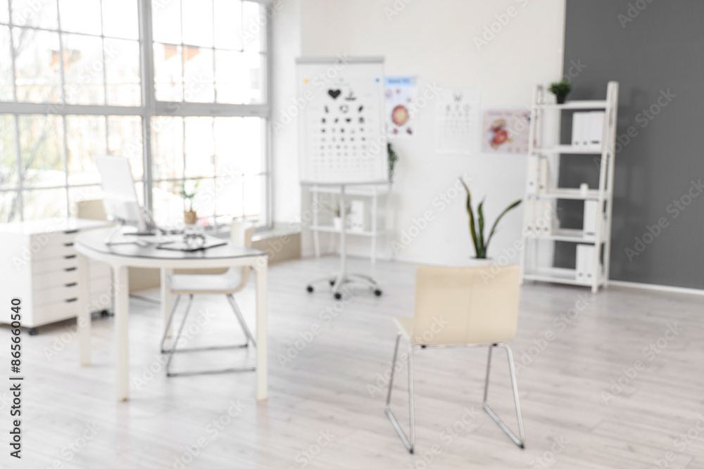 Fototapeta premium Blurred view of oculist's office with workplace and eye test charts