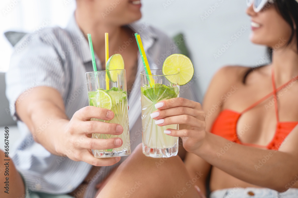 Happy young tourists couple with glasses of mojito at home, closeup Happy young tourists couple with glasses of mojito at home, closeup