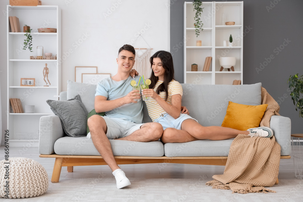 Happy young couple with glasses of mojito sitting on sofa at home Happy young couple with glasses of mojito sitting on sofa at home