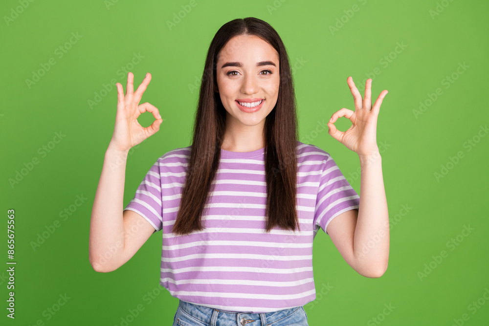 Photo portrait of pretty young girl show okey wear trendy striped violet outfit isolated on green color background Photo portrait of pretty young girl show okey wear trendy striped violet outfit isolated on green color background