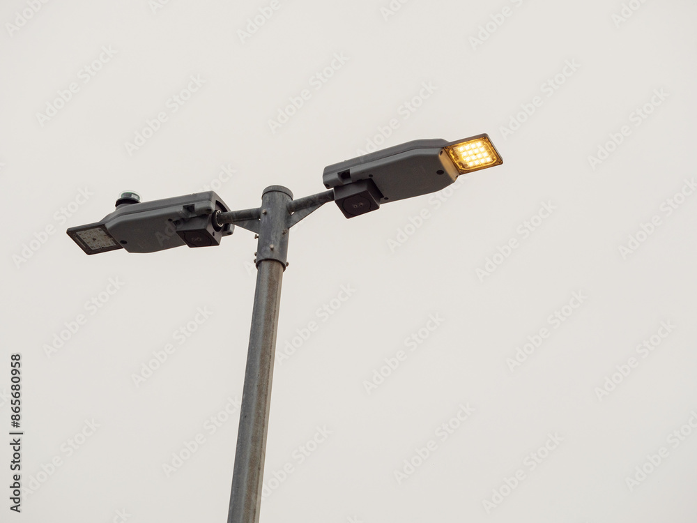 Modern LED light on a metal pole against grey sky. Copy space. Modern illumination technology with low running cost and high light output Modern LED light on a metal pole against grey sky. Copy space. Modern illumination technology with low running cost and high light output