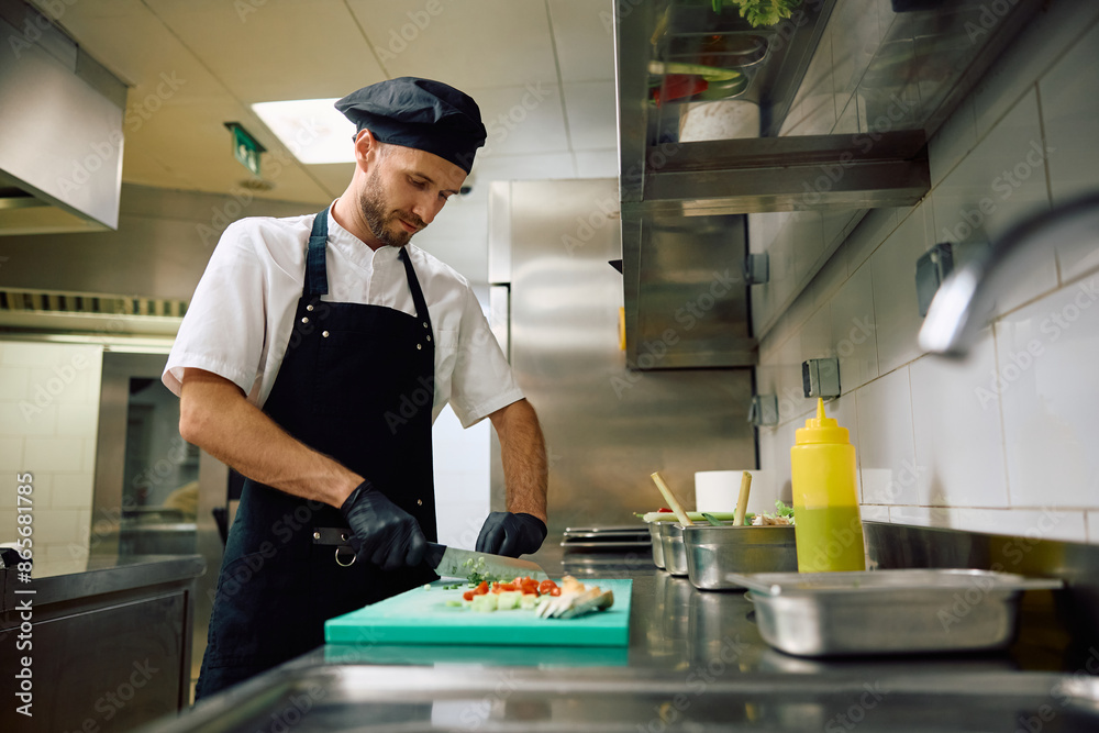 Restaurant cook chopping food while preparing meal in kitchen. Restaurant cook chopping food while preparing meal in kitchen.