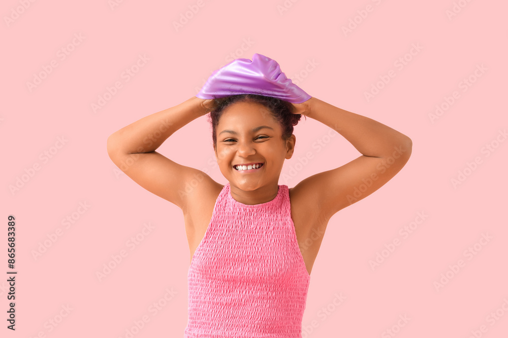 Happy African-American girl with swimming hat on pink background