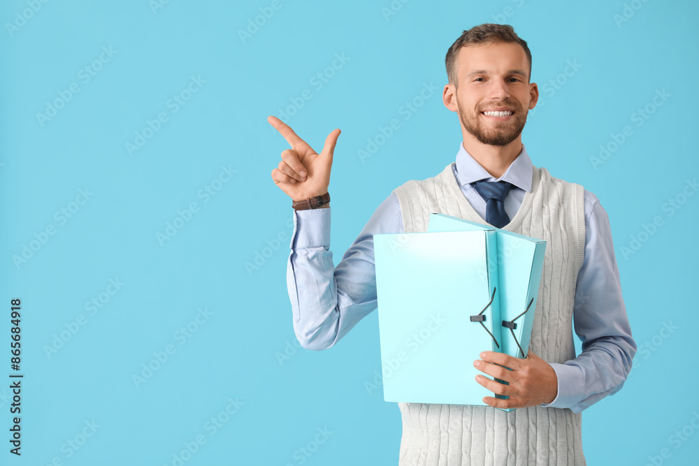 Young businessman with folders pointing at something on blue background Young businessman with folders pointing at something on blue background