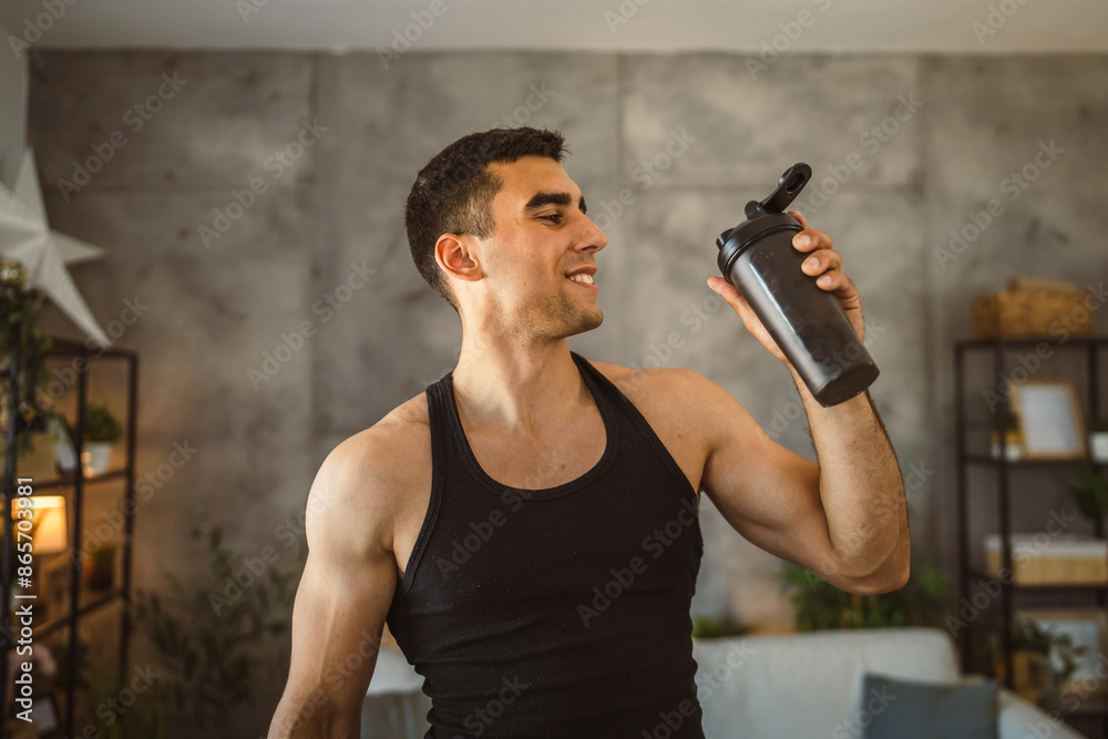 Portrait of young man stand and hold shaker in the living room