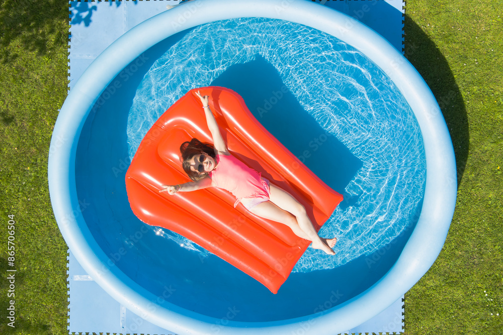 Φωτογραφία Little girl child sunbathes on an air mattress in a swimming pool outdoors on a summer day