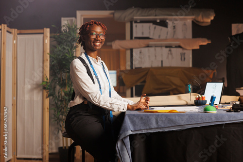 Portrait of happy african american seamstress entrepreneur working in black owned atelier shop business. Professional smiling couturier designing sartorial bespoken outfits for upcoming comission photo