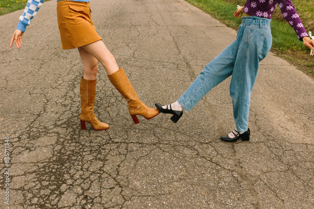 Two friends performing a playful kick dance on a street Two friends performing a playful kick dance on a street