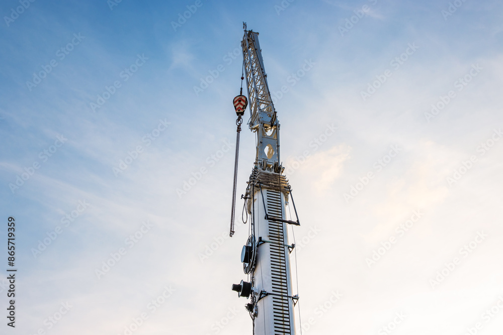 Construction crane arm with hook with cable against clear blue sky background. Industrial equipment or tools. Copy space. Selective focus. Construction crane arm with hook with cable against clear blue sky background. Industrial equipment or tools. Copy space. Selective focus.