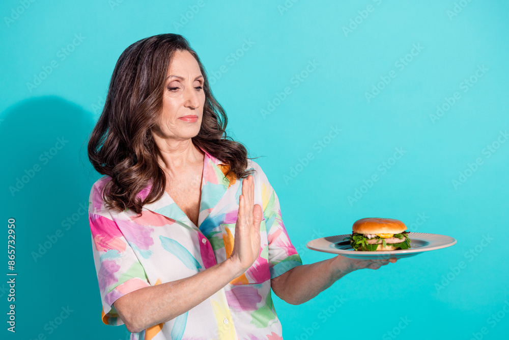 Photo portrait of attractive senior woman refuse burger unhealthy food dressed stylish colorful clothes isolated on cyan color background