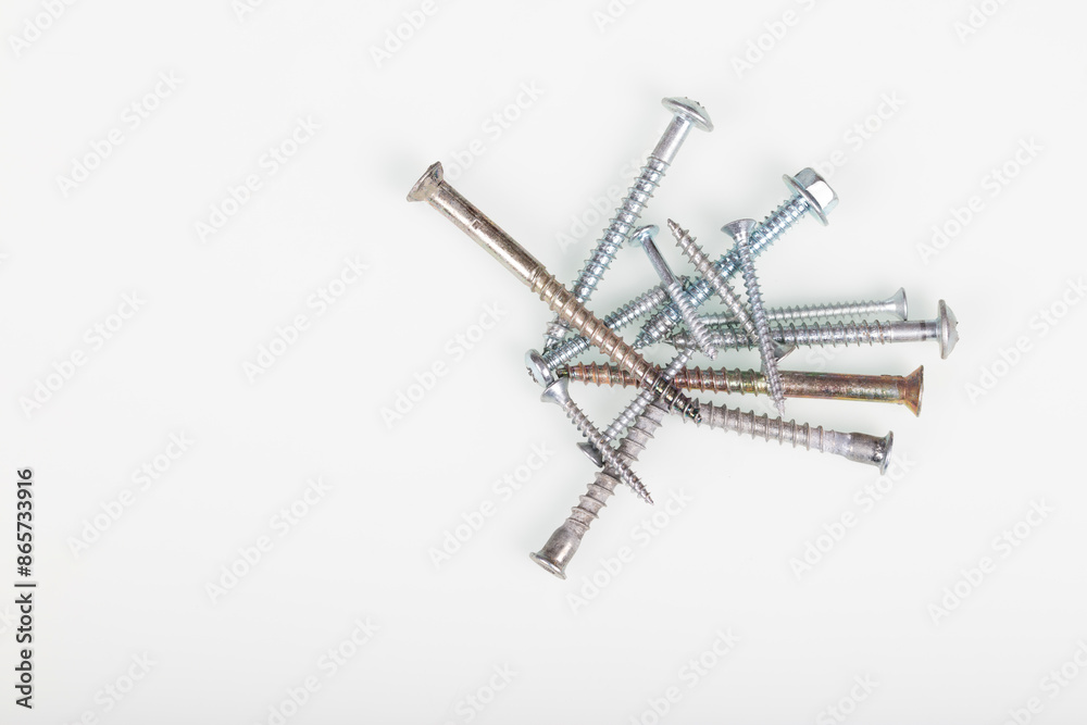 Assorted Metal Screws in Black and White. Close-up macro photograph of various metal screws scattered on a white background. Assorted Metal Screws in Black and White. Close-up macro photograph of various metal screws scattered on a white background.