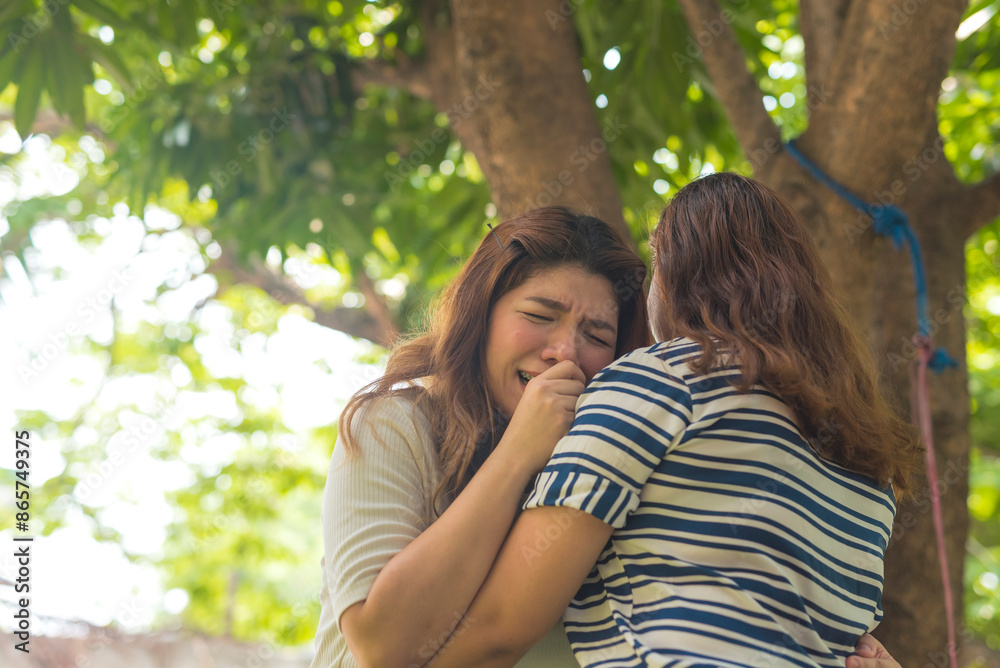 A woman consoles her hurt friend who is crying, providing emotional support and reassurance. The scene takes place outdoors under a tree. A woman consoles her hurt friend who is crying, providing emotional support and reassurance. The scene takes place outdoors under a tree.
