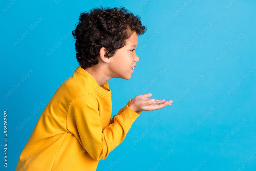 Profile portrait of cute small schoolkid hold empty space wear pullover isolated on blue color background Profile portrait of cute small schoolkid hold empty space wear pullover isolated on blue color background