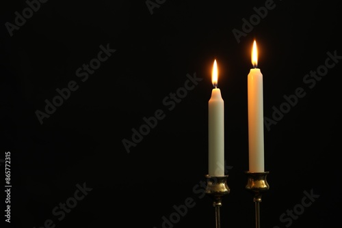 Burning candles on black background. Space for text