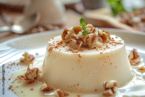 Vanilla panna cotta or jelly custard pudding with cream sauce and chopped nuts on a plate. photo