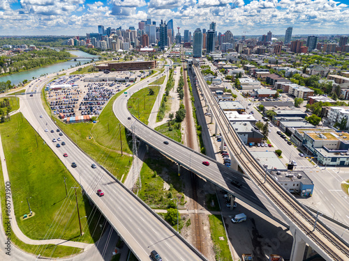 Calgary skyline aerial overlooking commuter traffic and elevated public transit lines with Canadian landmarks at background in Alberta Canada.