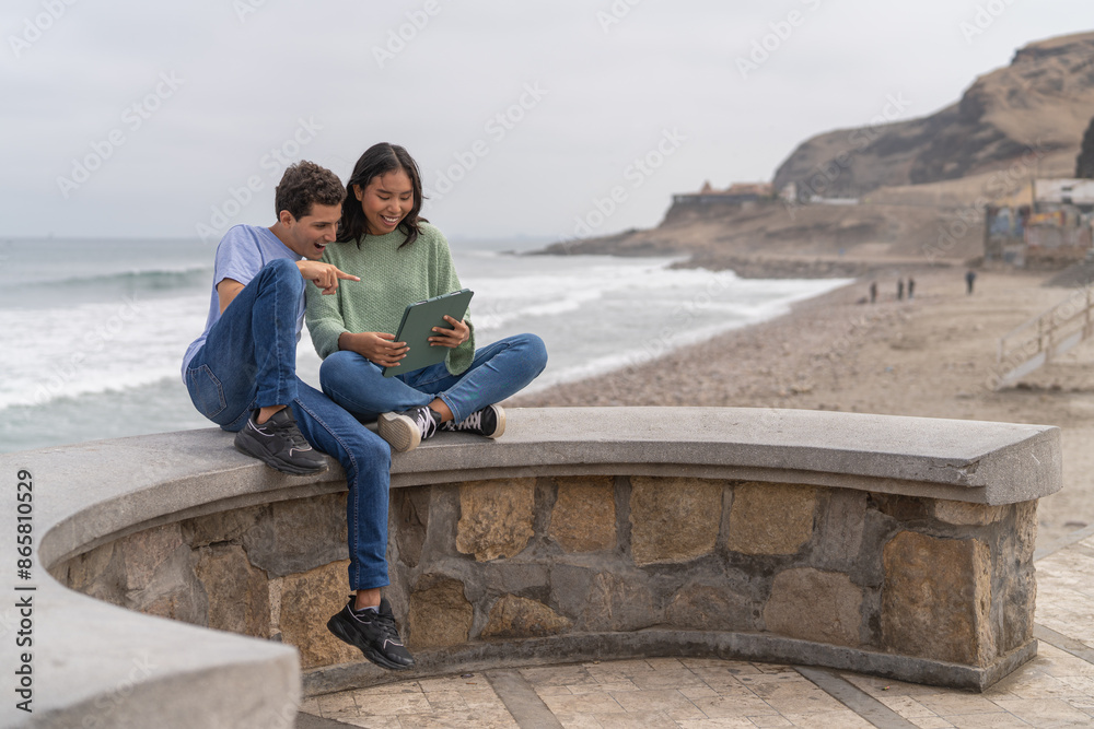 Couple enjoying sea views and sitting using digital tablet Couple enjoying sea views and sitting using digital tablet