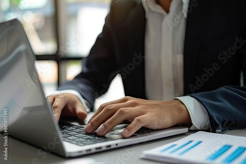 Close-up of businessman working on laptop computer on wooden desk in modern office © ttonaorh