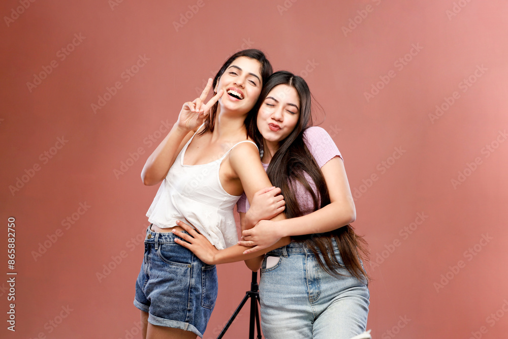 Two Female Friends Are Posing In Front Of The Camera And Making Victory Hand Sign Two Female Friends Are Posing In Front Of The Camera And Making Victory Hand Sign