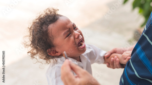 фотографія A young asian boy with curly hair crying and throwing a tantrum after not getting his toy back