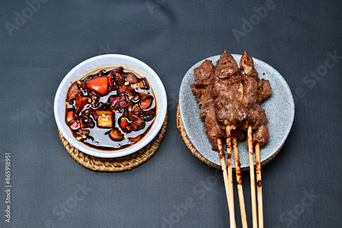 Satay with peanut sauce and soy sauce topped with chili slices and shallots is an Indonesian delight. Juicy grilled meat skewers paired with rich, spicy, and savory sauces