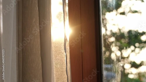 Slow motion of the curtains on the window There was morning light streaming through the bedroom window. Look out over the mountains and trees as the sun rises.