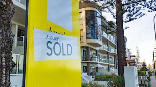 Real estate for sale sign with sold sticker in front of Gold Coast apartment building