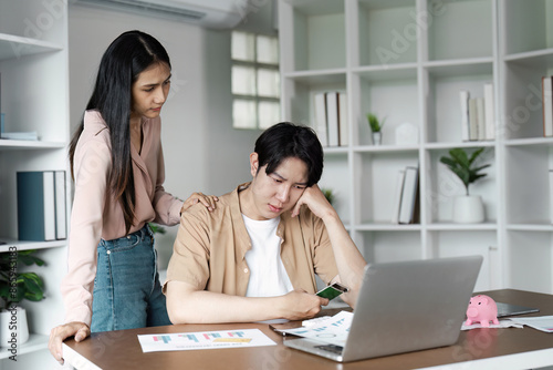 Young Couple Discussing Financial Planning and Savings While Experiencing Stress at Home with Laptop and Documents