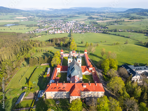 An aerial view of Hora Matky Bozi Monastery, located in Dolni Hedec near Kraliky, Czechia. The monastery is surrounded by lush greenery and a scenic landscape. photo