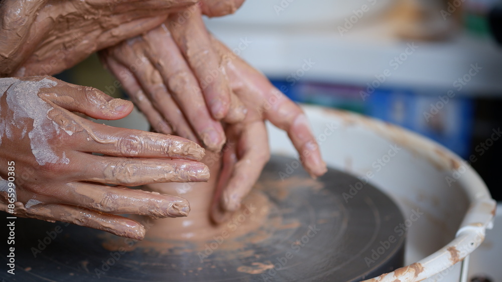An instructor teaching a student how to make pottery clay using on throwing wheel. An instructor teaching a student how to make pottery clay using on throwing wheel.