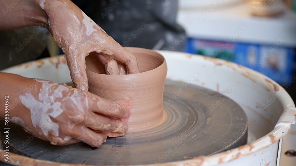 Smoothing clay pottery with sponge at throwing wheel. Smoothing clay pottery with sponge at throwing wheel.