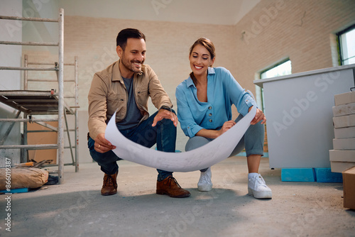 Happy couple analyzing blueprints during home renovation process. photo