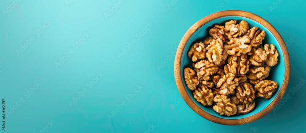 Close-up from above view of walnut kernel halves in a wooden bowl on a colored background, highlighting the healthy eating concept of superfoods with available copy space image. Close-up from above view of walnut kernel halves in a wooden bowl on a colored background, highlighting the healthy eating concept of superfoods with available copy space image.