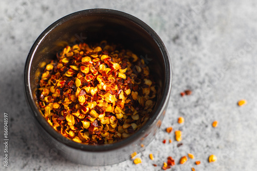 selective focus of sun dried red chilli flakes on a black bowl. 