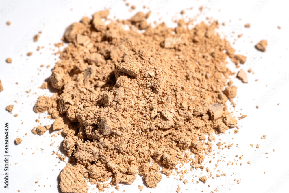 Scattered tan colored facial loose powder on white background. Top view . Scattered tan colored facial loose powder on white background. Top view .