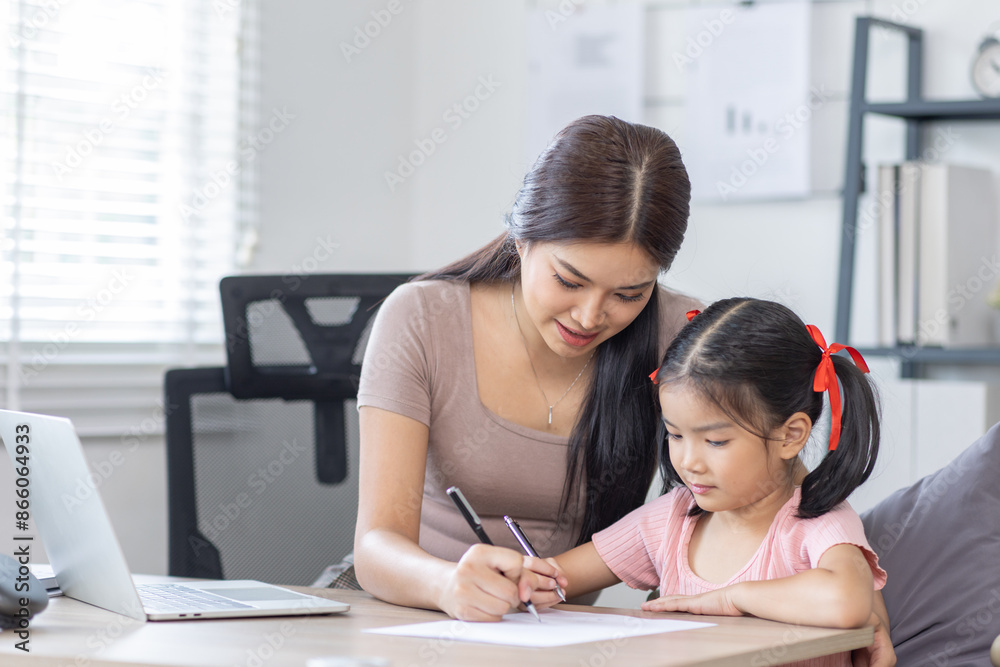 Asian business lady working on computer while her daughter hugging her Asian business lady working on computer while her daughter hugging her