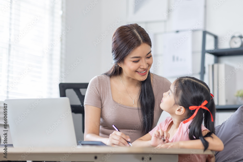 Asian business lady working on computer while her daughter hugging her Asian business lady working on computer while her daughter hugging her
