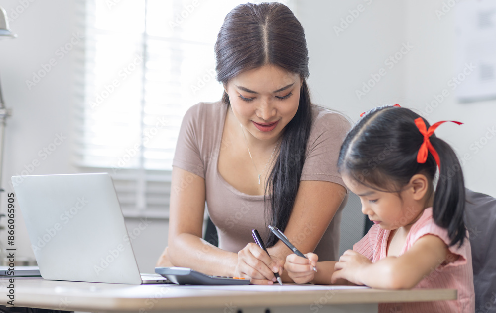 Asian business lady working on computer while her daughter hugging her Asian business lady working on computer while her daughter hugging her