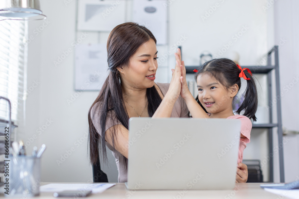 Asian business lady working on computer while her daughter hugging her Asian business lady working on computer while her daughter hugging her