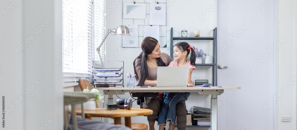 Asian business lady working on computer while her daughter hugging her Asian business lady working on computer while her daughter hugging her