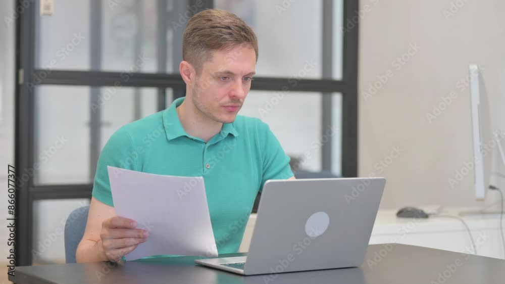 Casual Young Man Working on Documents and Laptop Casual Young Man Working on Documents and Laptop