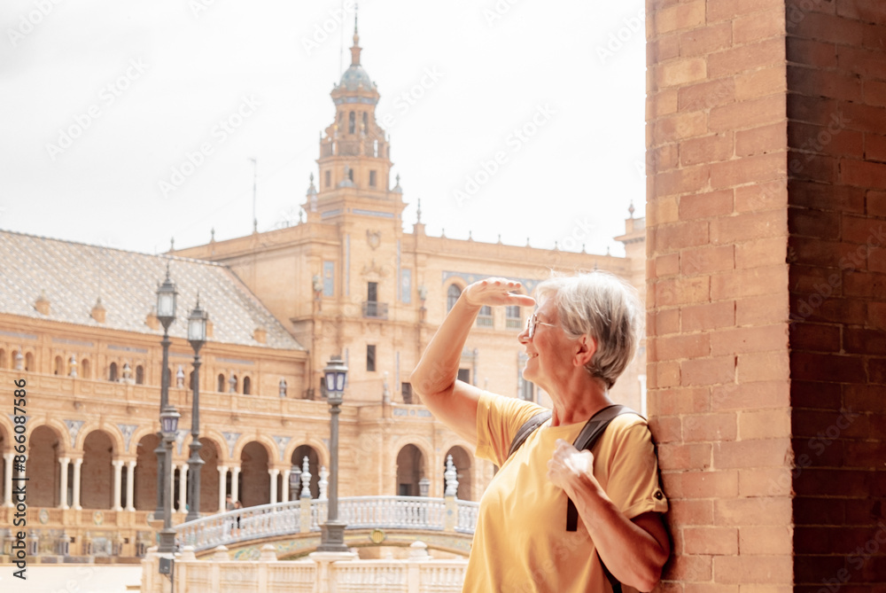 Φωτογραφία Happy senior woman tourist in yellow visiting Plaza de Espana in Seville
