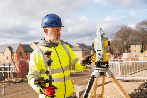 Construction Worker Using Surveying Equipment on Sunny Day photo