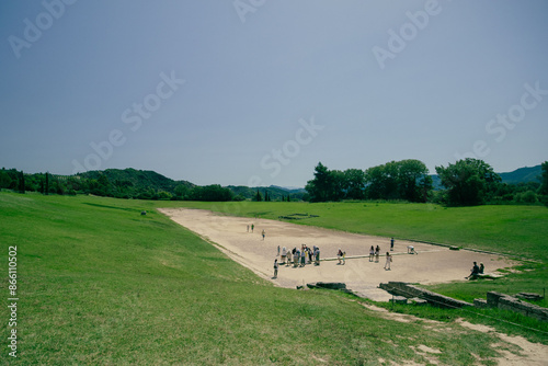 Ancient stadium in Olympia, greece on a hot summer day. Visible tourists and field where different games were held. photo