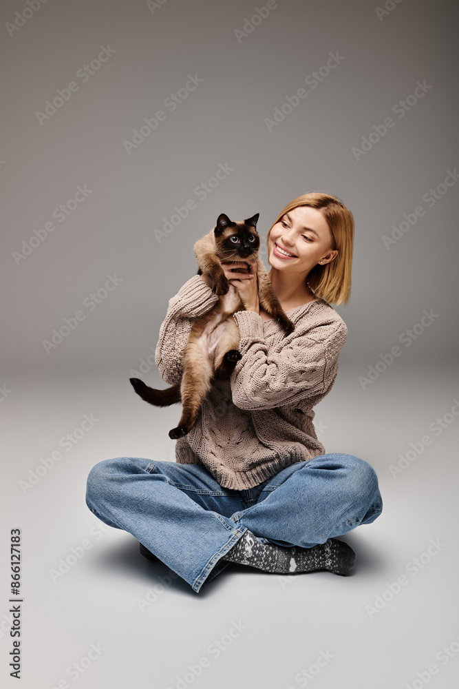 A woman with short hair finds peace while sitting on the floor and holding her beloved cat in her arms. A woman with short hair finds peace while sitting on the floor and holding her beloved cat in her arms.