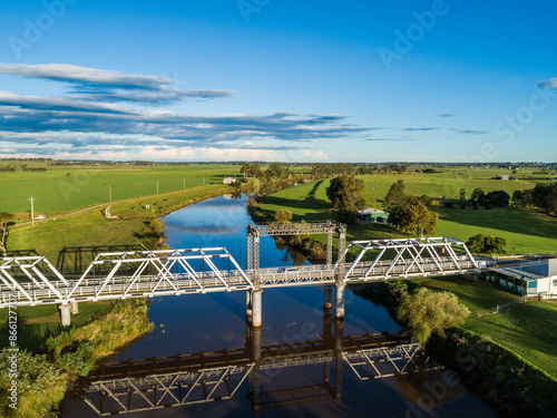 Paterson River and heritage listed bridge in green farmland waterway reflecting blue sky photo