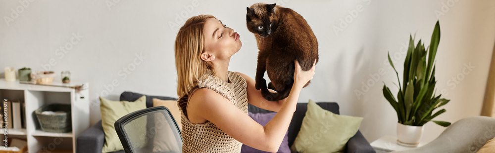 Obraz premium A woman with short hair holds her cat close to her face, sharing a moment of love and connection at home.