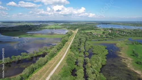 Flying from above over the road, on both sides of it flooded fields and meadows. Reflection of clouds in the water. Vyshnevolotsk water system. Beautiful spring landscape